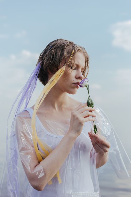 Free A serene portrait of a woman holding a flower in a dreamy outdoor setting. Stock Photo