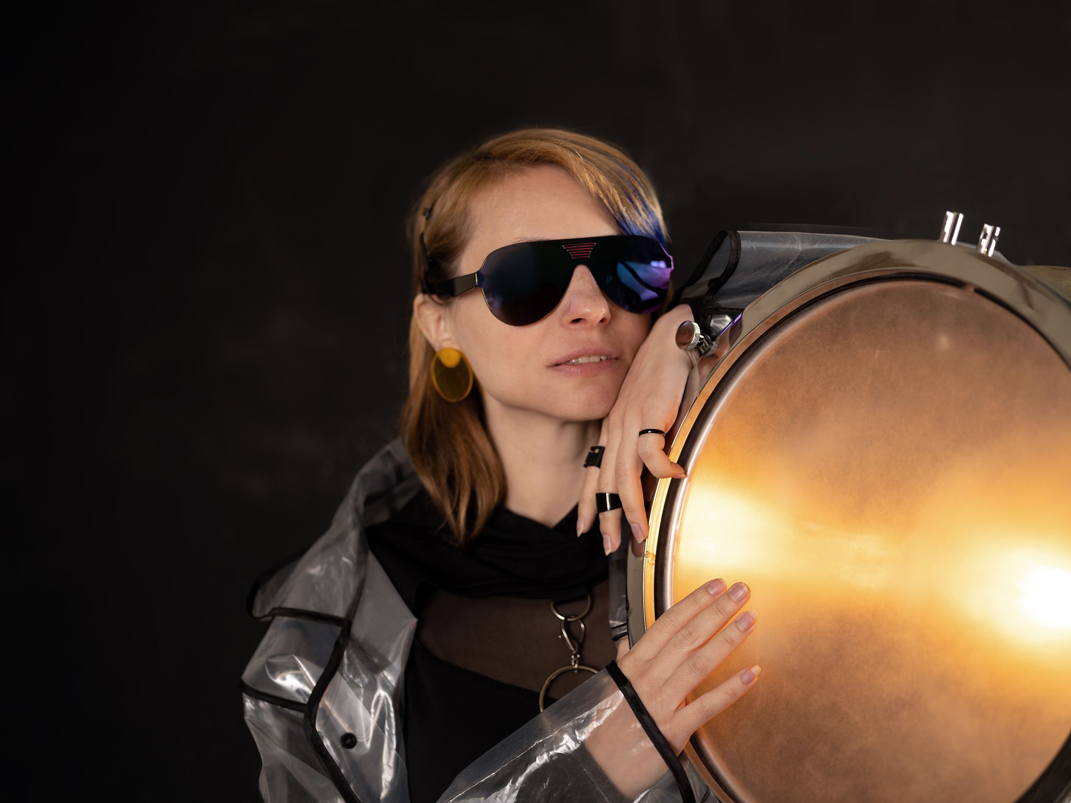 Stylish woman posing with sunglasses and glowing light in a studio shoot.