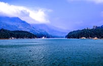 在多云的天空下，郁郁葱葱的森林和山脉环绕着宁静的湖泊