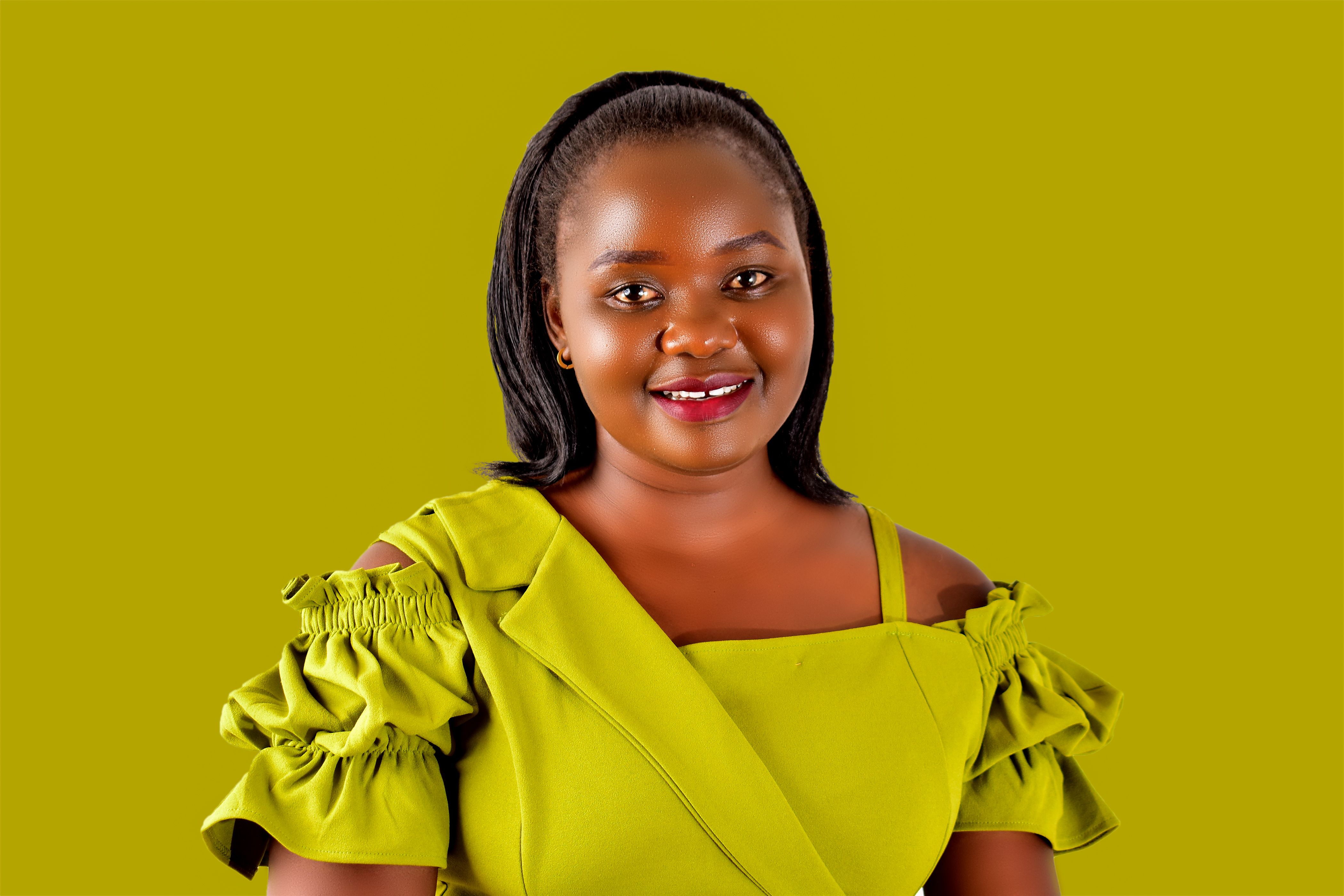 Charming portrait of a smiling woman in an elegant green dress against a yellow background.