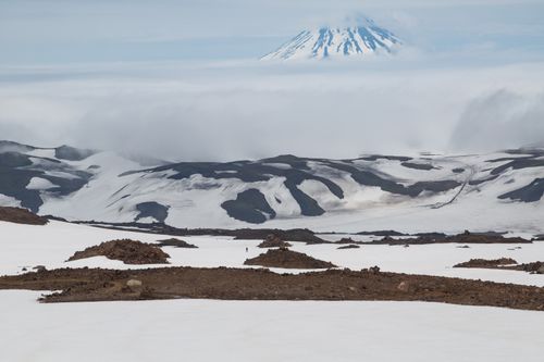 Free Breathtaking view of a snow-covered volcanic terrain with a mountain peak shrouded in clouds. Stock Photo