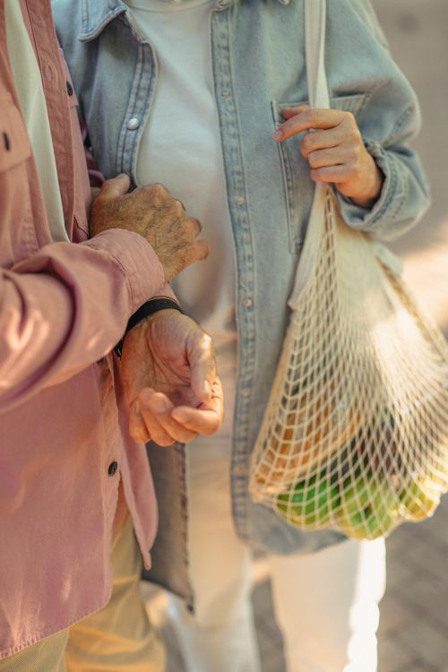 Free Senior couple shopping with a mesh bag filled with fruits outdoors. Stock Photo