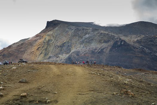 A group of hikers traverse the rugged terrain near a colorful, rocky mountain in an adventurous landscape.