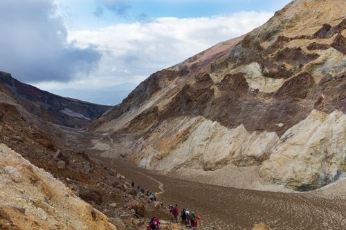 Free Group of hikers on a scenic trek through a rugged mountain valley under a cloudy sky. Stock Photo