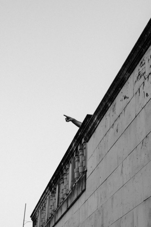 Free Black and white image of a building facade and pointing hand from a balcony. Stock Photo
