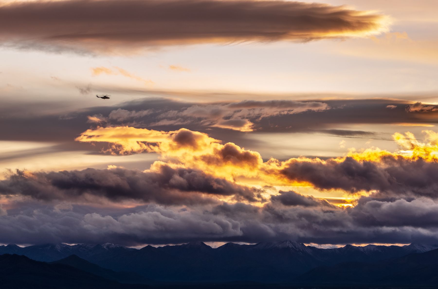 Silhouette of a helicopter against a sunset sky