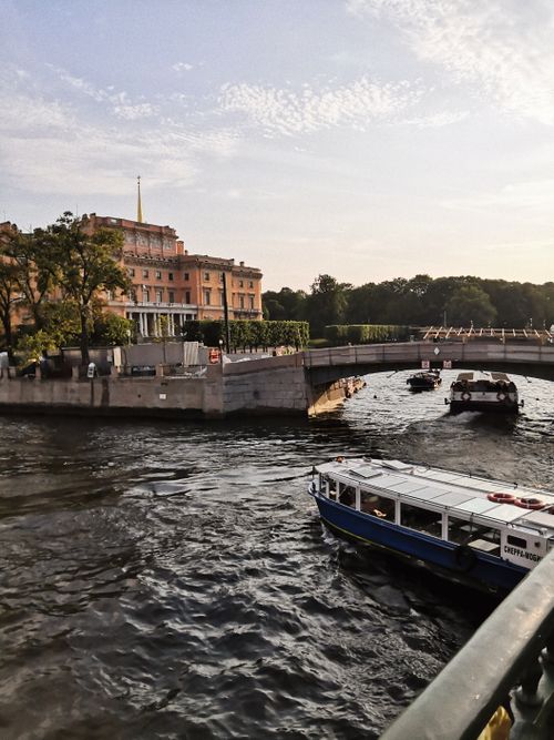 Free River scene with boats passing under a picturesque bridge near historic buildings. Stock Photo