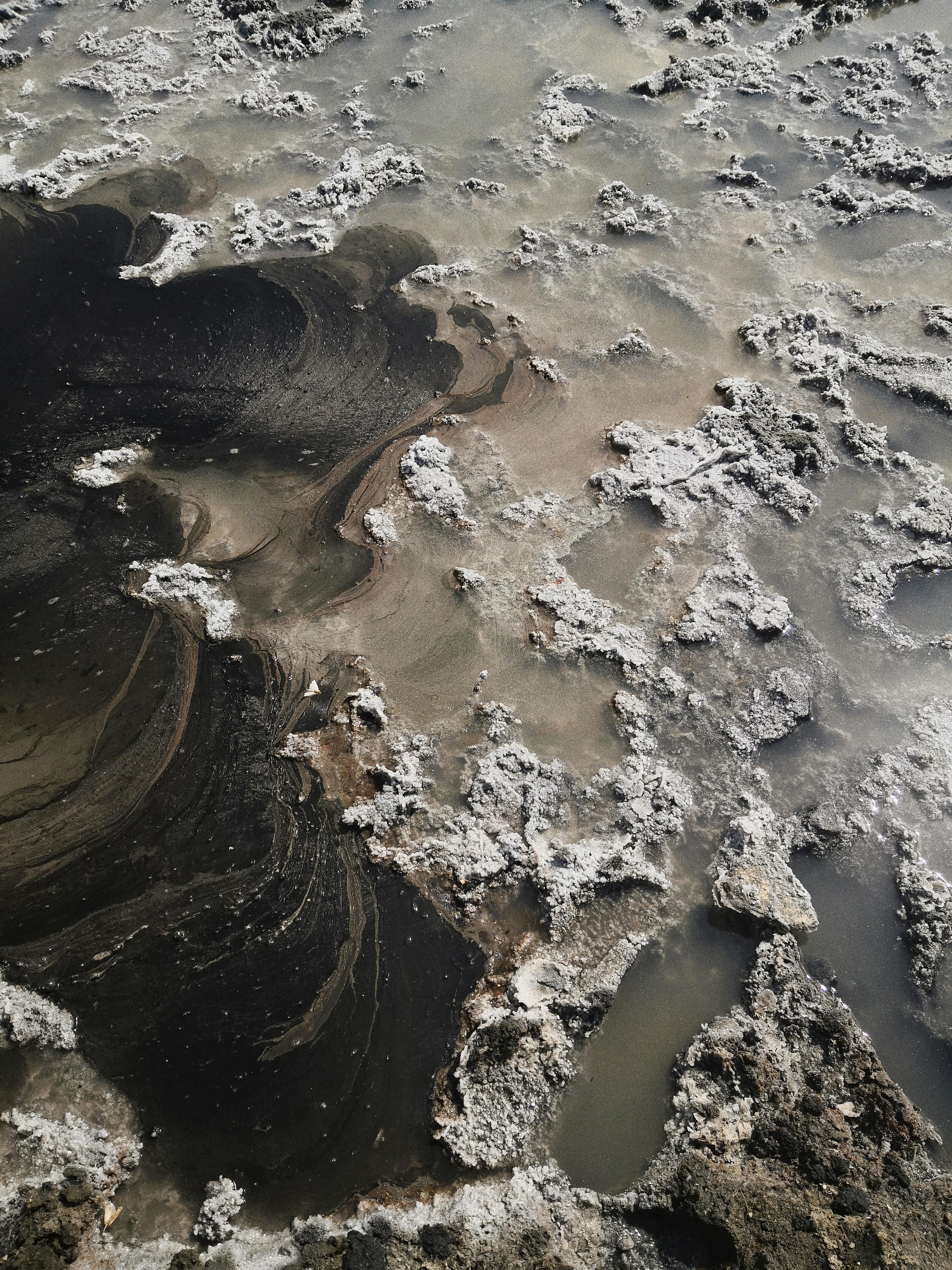 Abstract aerial photograph showcasing intricate salt patterns on a black sand beach.