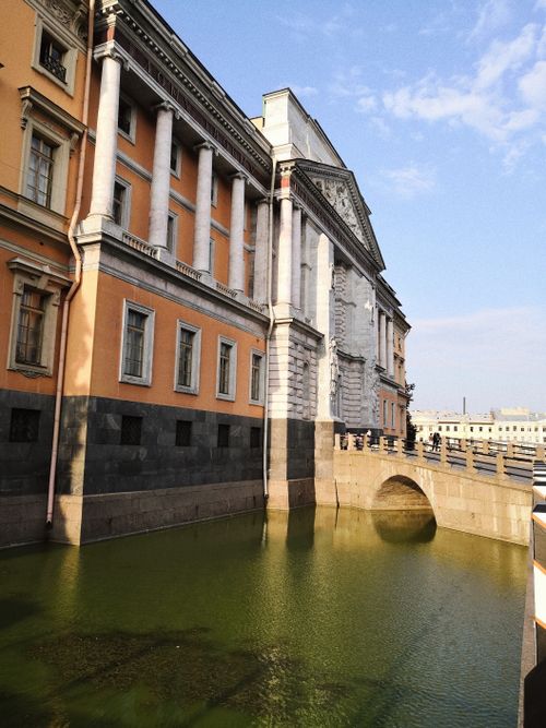 Free A striking view of a historic building by a tranquil canal under a clear sky. Stock Photo