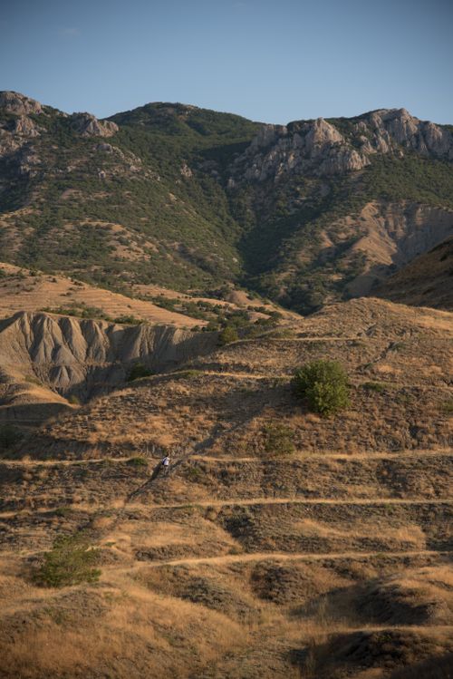 Free A lone hiker navigates rugged paths in a striking mountainous desert landscape. Stock Photo