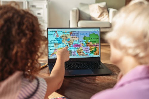 Free A Person Pointing at a Map on a Laptop Stock Photo