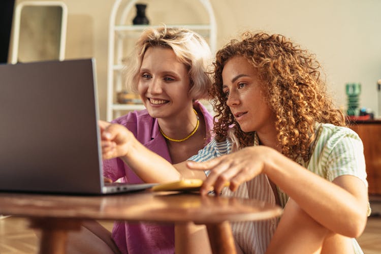 Women Sitting On The Ground Looking At The Silver Laptop 