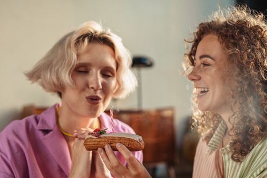 A joyful couple celebrating with an eclair topped with a lit candle.