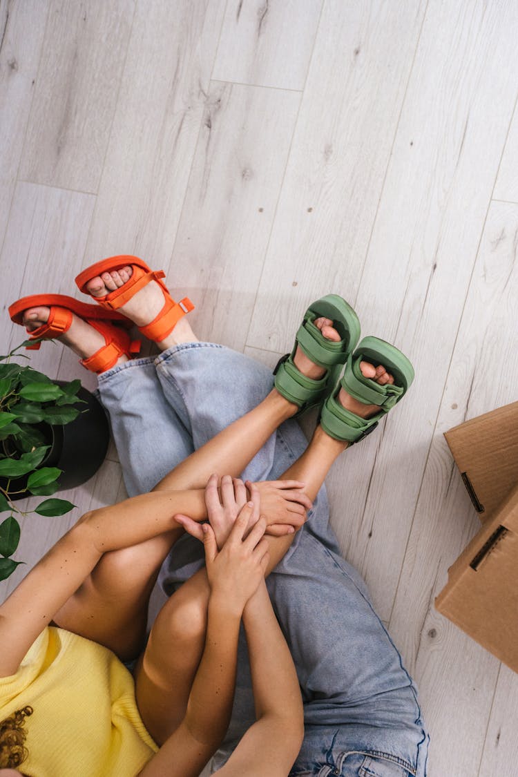 People Sitting On The Wooden Floor Wearing Matching Sandals