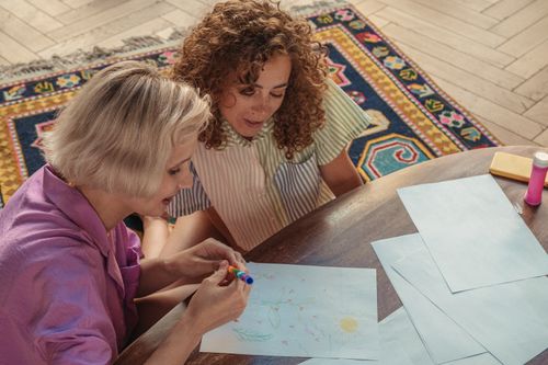 Free Two women enjoying a creative drawing session indoors with colorful markers and papers. Stock Photo