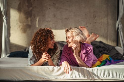 Free A happy lesbian couple with short and curly hair shares a joyful moment indoors on a bed. Stock Photo