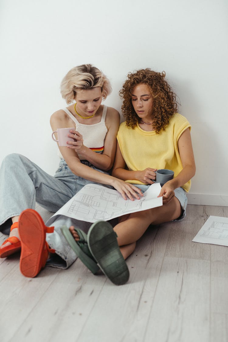 Women Sitting In The Floor Looking At A Blueprint