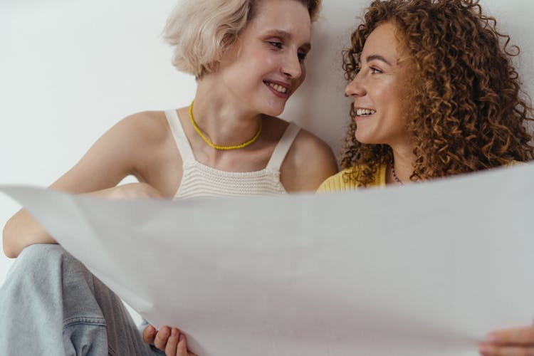 A Smiling Couple Looking At Each Other While Holding A Paper