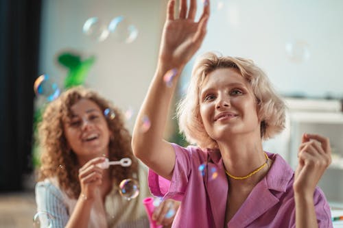 Free Close-Up Shot of Two Happy Women Playing Bubbles Stock Photo