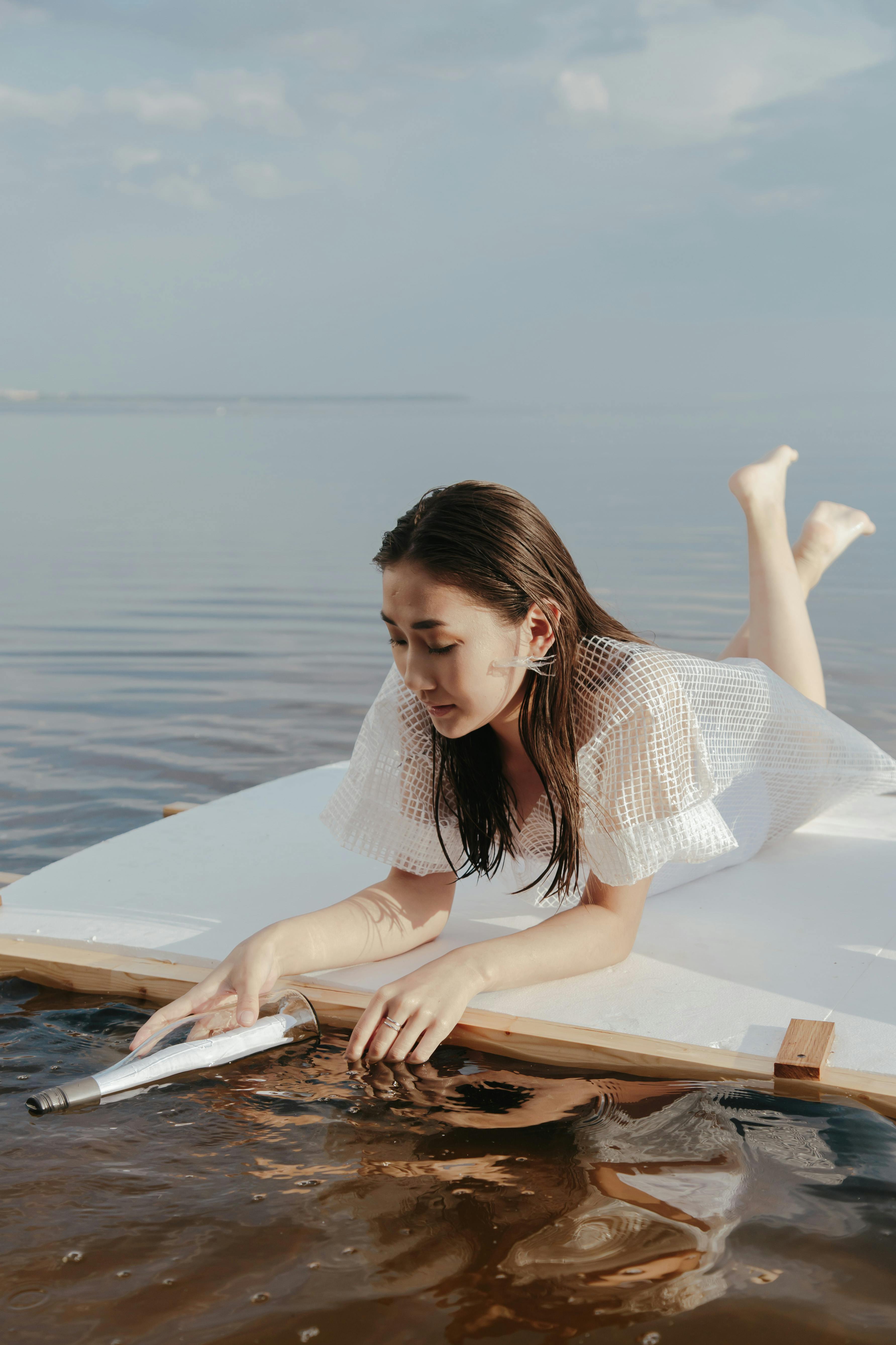 一名亚洲女子在平静的海滩水上的浮动平台上享受宁静的时刻