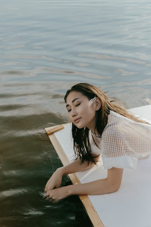 Free A Woman in White Dress Sitting on the Raft Stock Photo