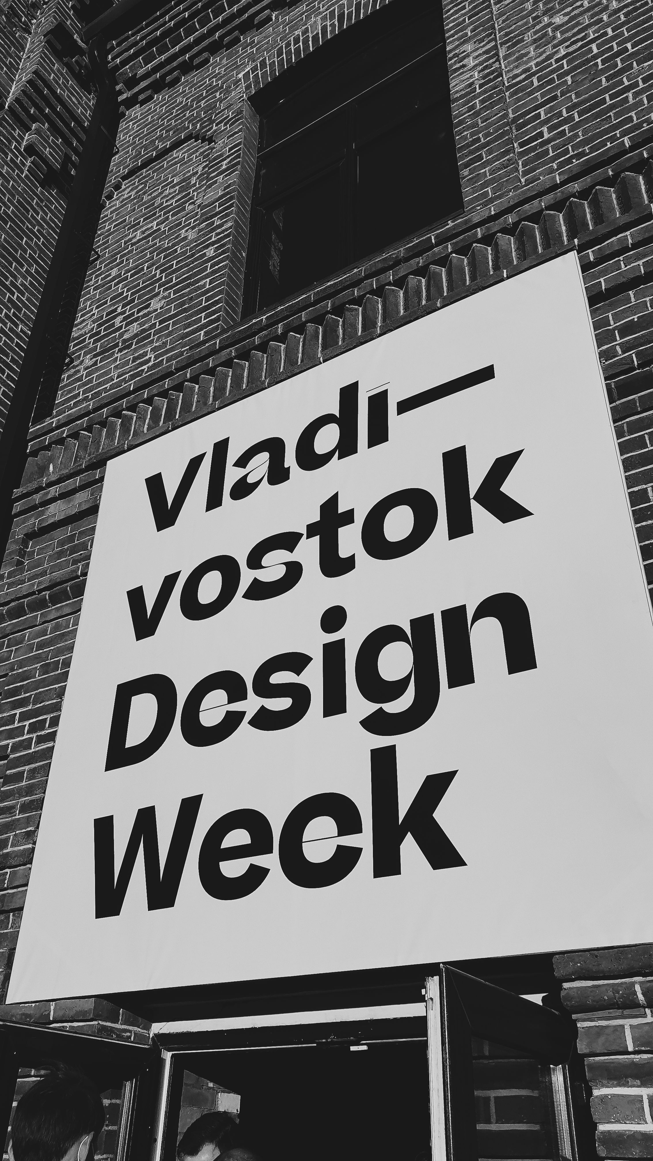 Grayscale photo of Vladivostok Design Week signage on a building facade.