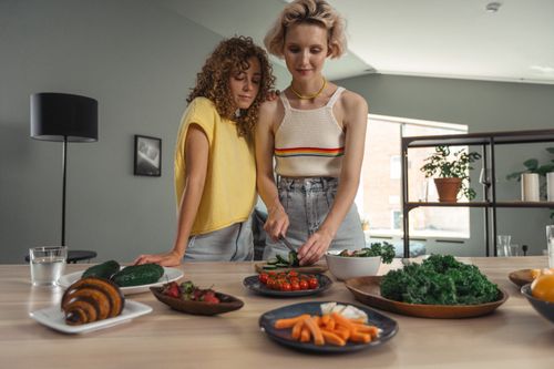 Free Couple cooking together in a modern kitchen, preparing a healthy meal with fresh vegetables, symbolizing a wholesome lifestyle. Stock Photo