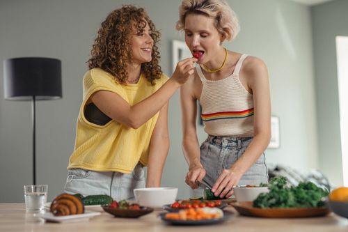 Free Two women joyfully preparing a meal indoors, highlighting love and happiness. Stock Photo
