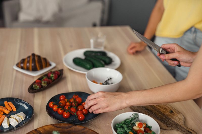 Persona cortando y organizando frutas y verduras frescas para preparar comidas saludables durante la ventana de alimentación