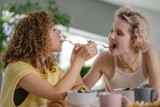 Two women sharing a meal indoors, fostering connection and joy.