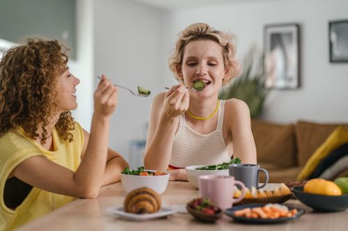 Free Two women enjoying a healthy meal at a cozy dining table, sharing a joyful indoor breakfast moment. Stock Photo