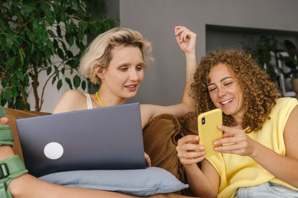 Two people sharing a laptop and phone at home, photo by SHVETS production on Pexels