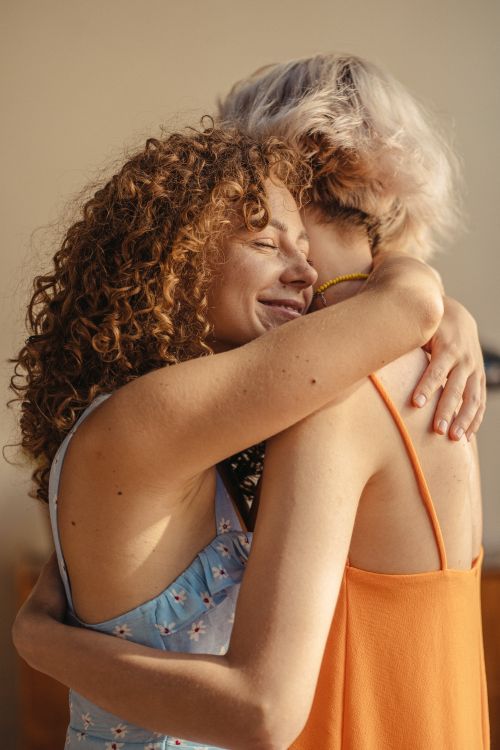 Free Two women joyfully embracing in a warm, sunny atmosphere, representing love and friendship. Stock Photo