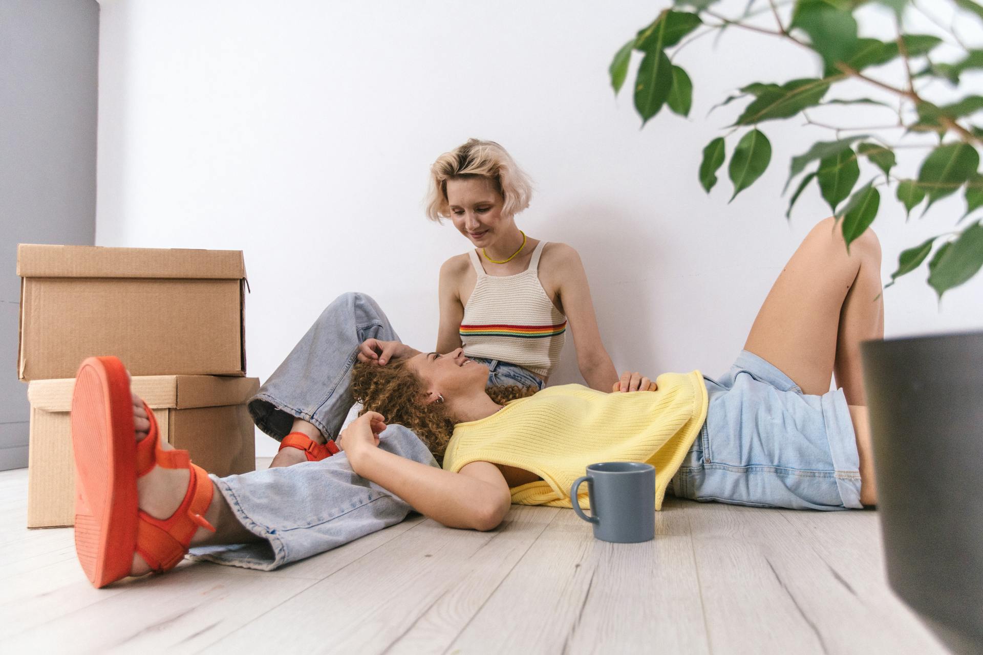 Happy couple relaxing indoors with moving boxes and a cup, embodying love and togetherness.