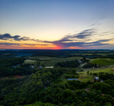 Stunning aerial view of Alma, Wisconsin countryside at sunset, showcasing lush green fields and vibrant sky.
