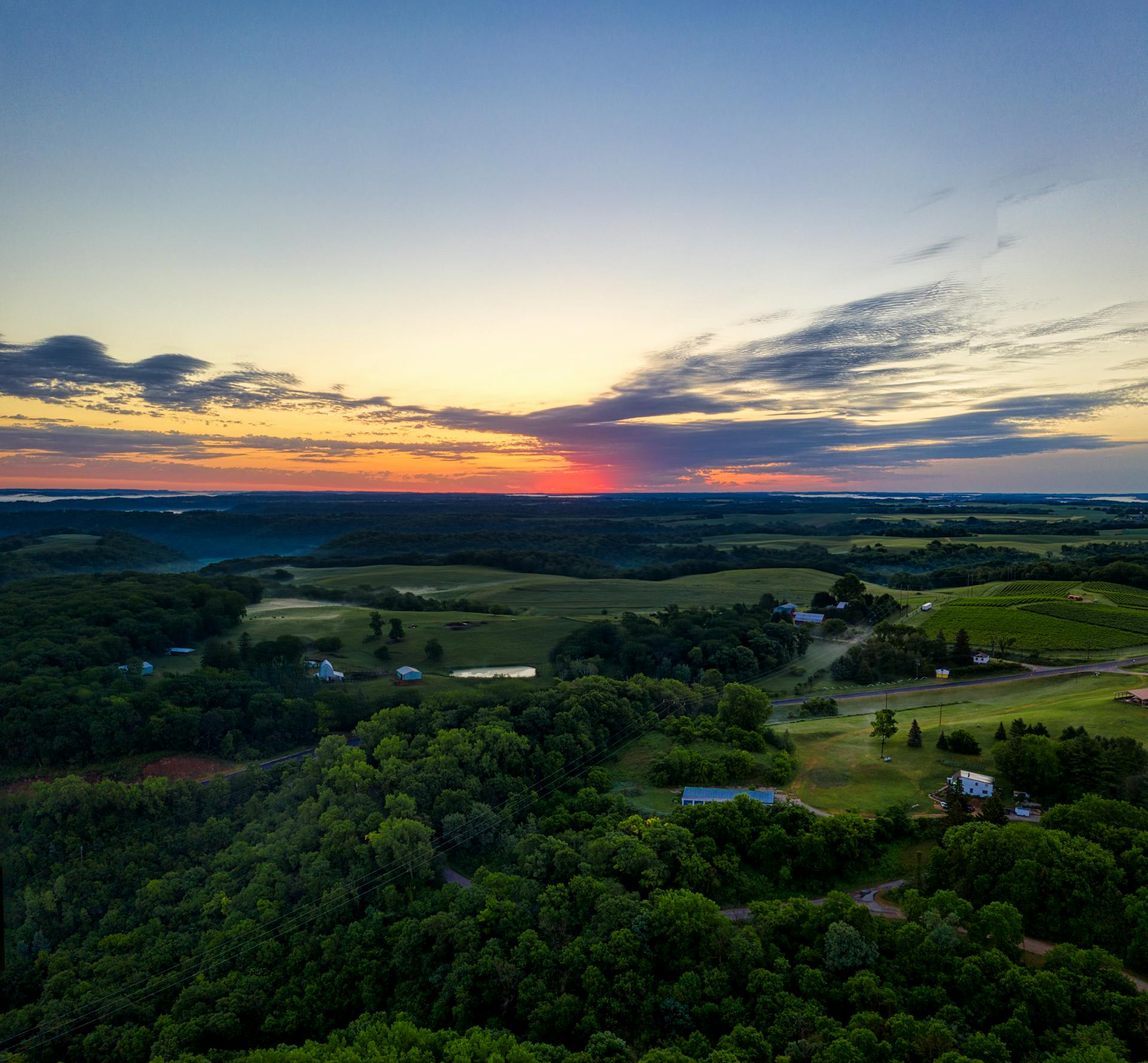 Stunning aerial view of Alma, Wisconsin countryside at sunset, showcasing lush green fields and vibrant sky.