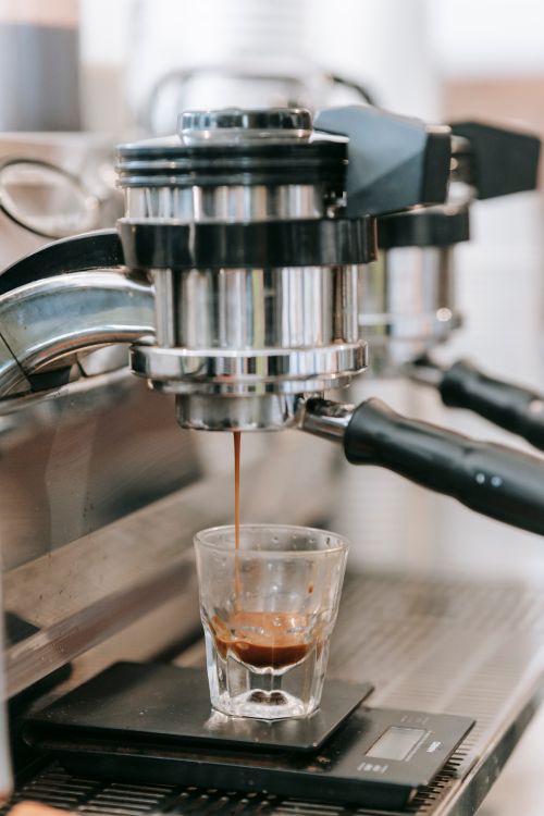 Free Close-up shot of espresso pouring into a glass from a coffee machine. Perfect for coffee shop visuals. Stock Photo