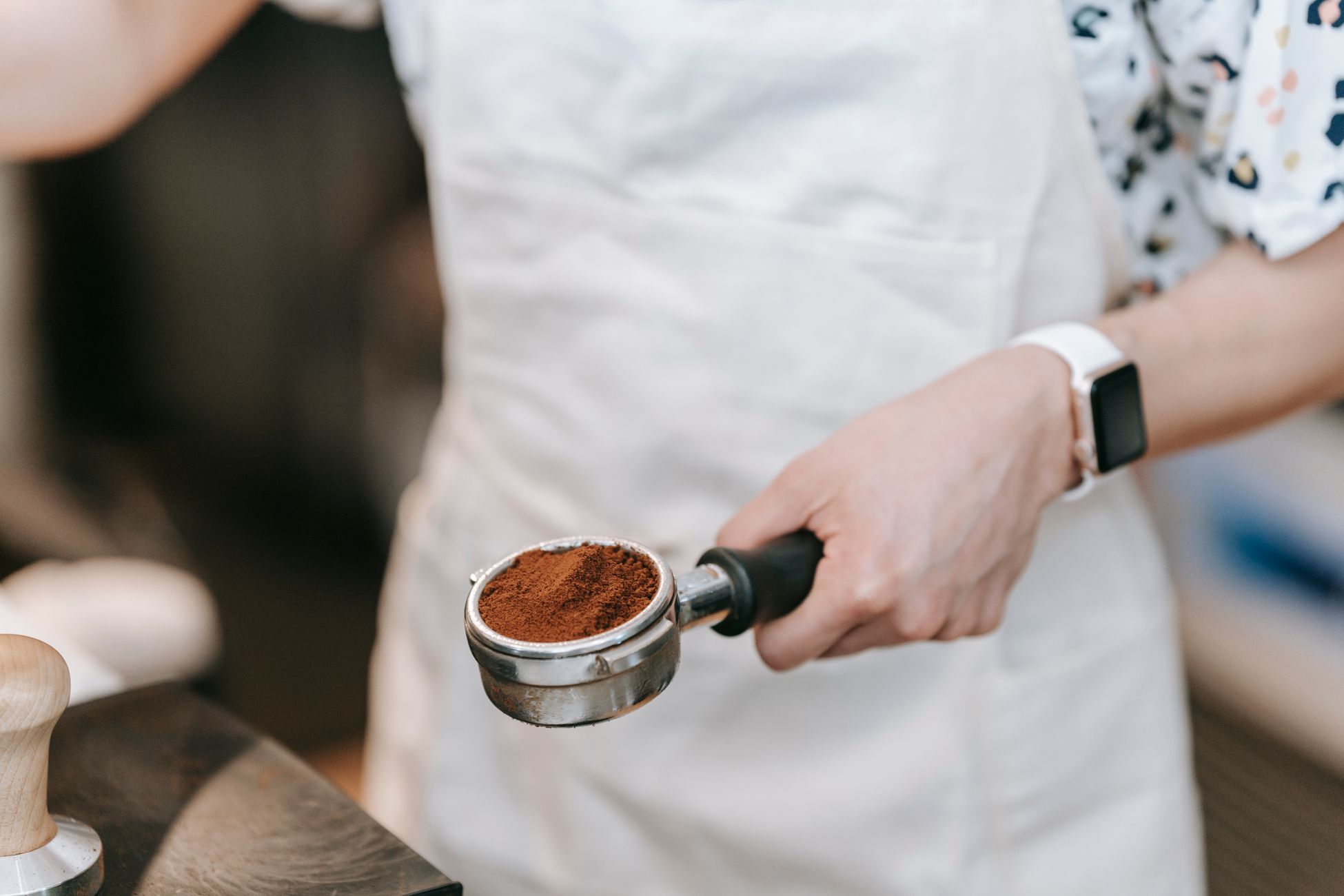 A barista holds a portafilter filled with freshly ground coffee, showcasing precision in coffee making.