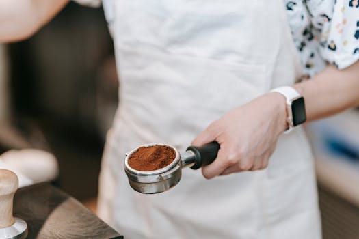 A barista holds a portafilter filled with freshly ground coffee, showcasing precision in coffee making.