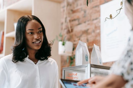 Warm interaction between a smiling barista and a customer inside a coffee shop.