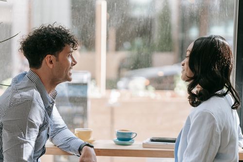 Free Two colleagues conversing over coffee by a window, enjoying a relaxed break indoors. Stock Photo