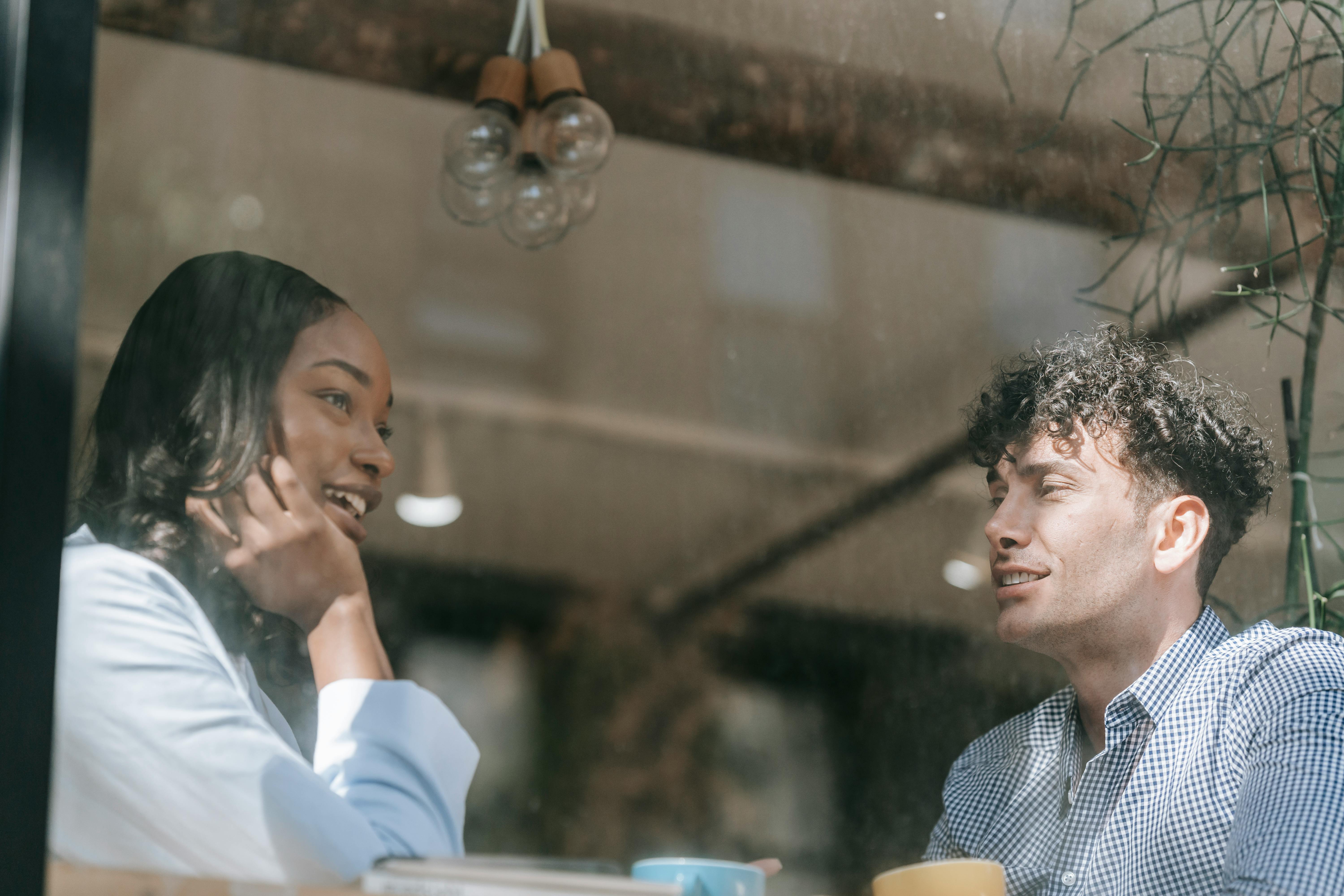 man and woman talking near the window