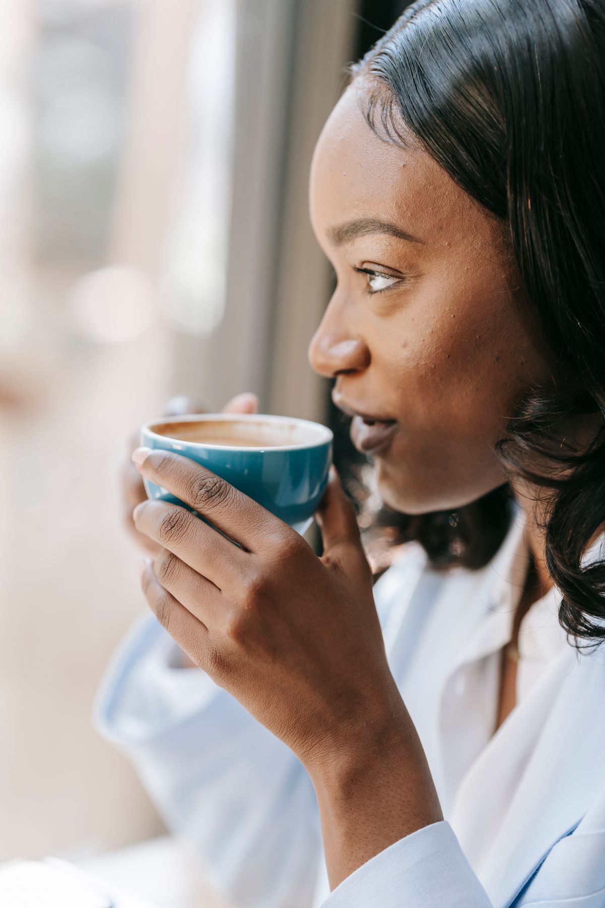 Mulher bebendo café enquanto olha pela janela