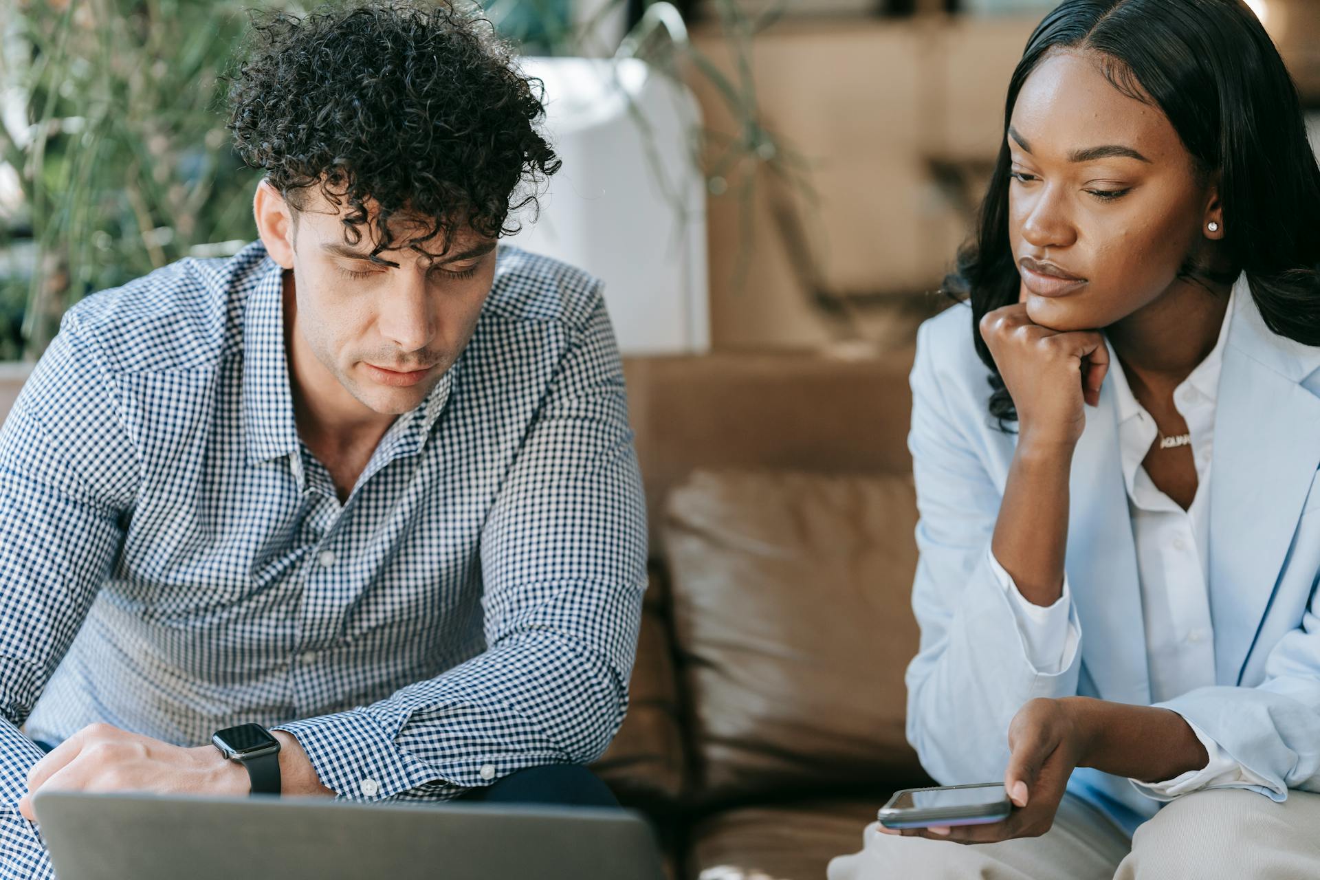 Two business professionals focused on work, collaborating with a laptop.