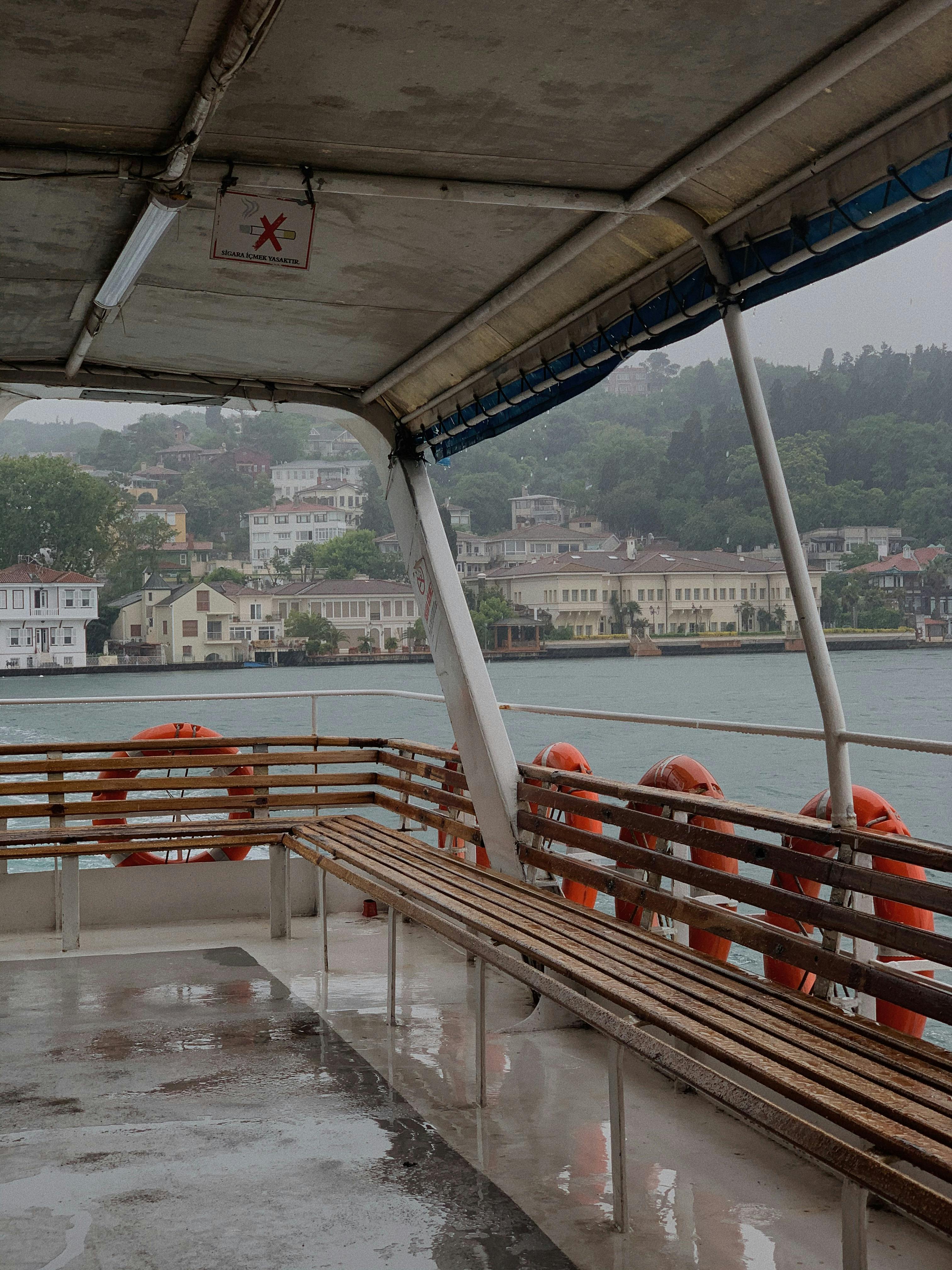 Free Empty ferry with waterfront view of Beykoz, Istanbul buildings in rainy weather. Stock Photo