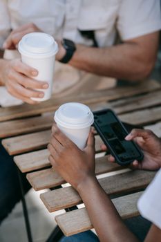 Two people enjoying coffee at a wooden table while using a smartphone.