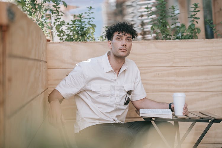 Man In White Button Up Shirt  Holding A Coffee Sitting On Chair