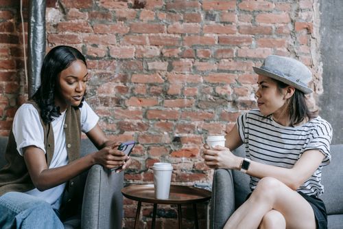 Free Two friends enjoying a coffee break indoors, sharing moments and conversations. Stock Photo
