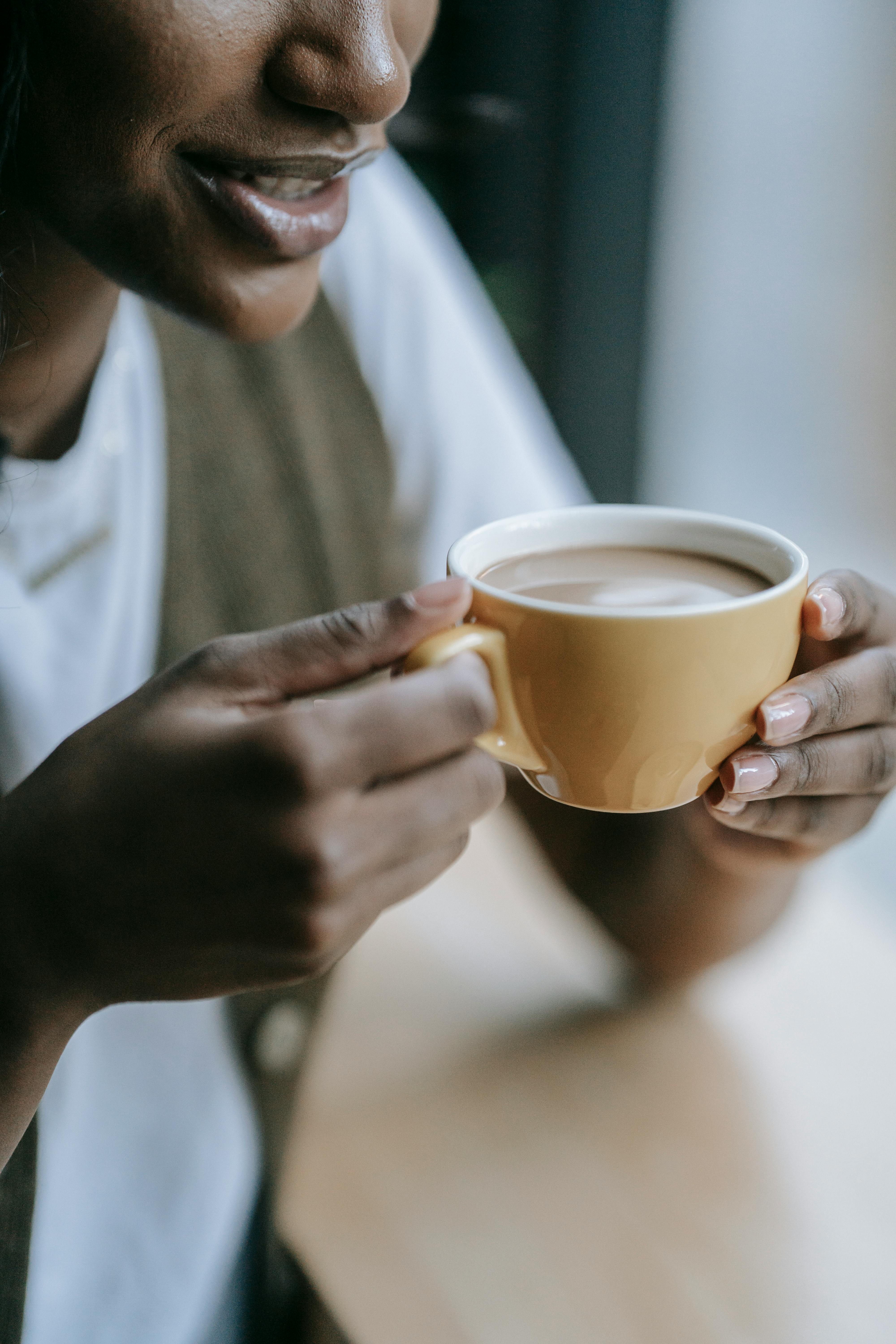 Close-up of a woman holding a cup of black coffee