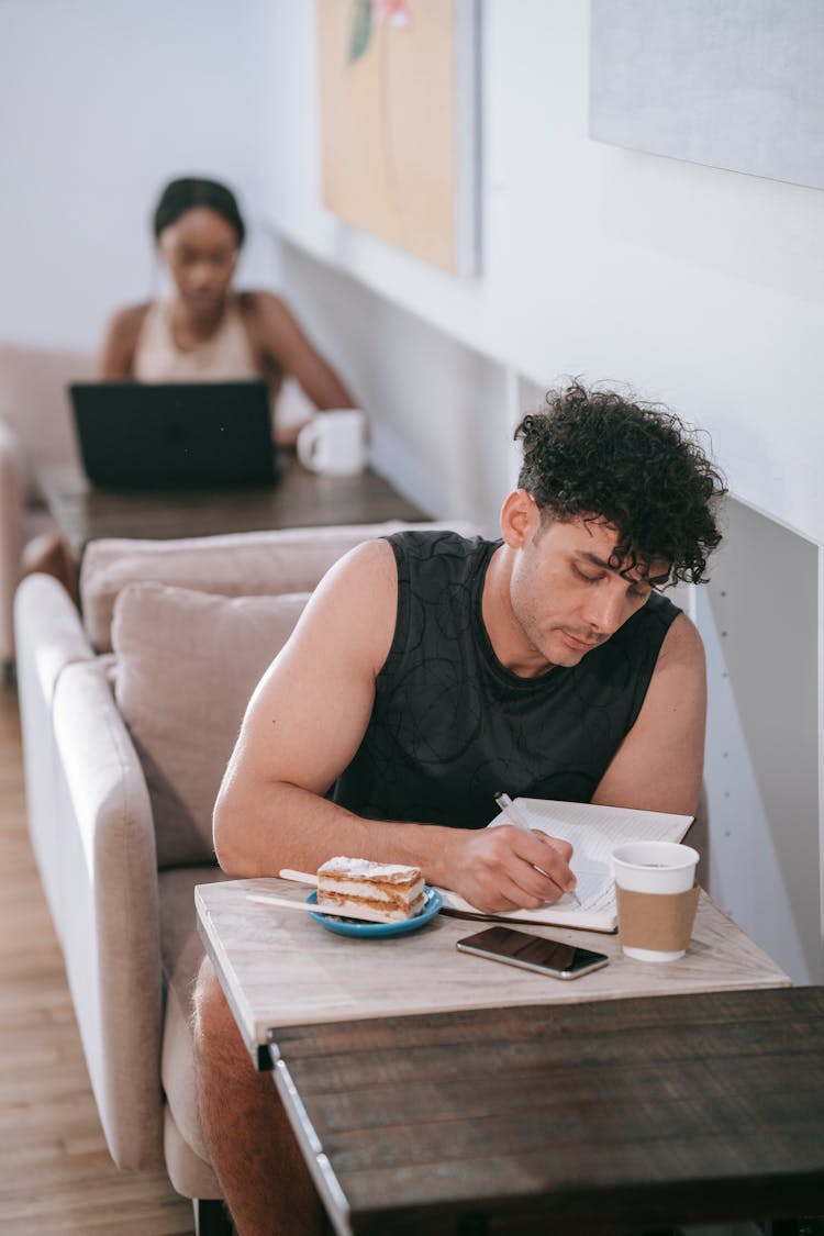 A Man Journaling At A Coffee Shop